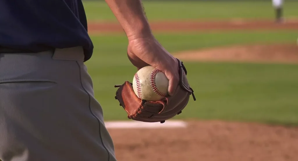 MLB pitcher gripping a baseball with the seams visible just before the start of his delivery
